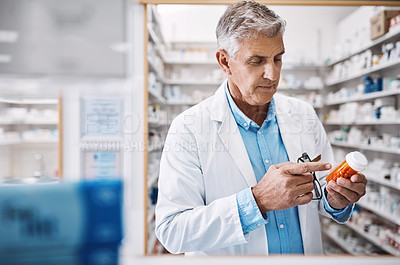 Buy stock photo Shot of a pharmacist reading the label on a product in a drugstore