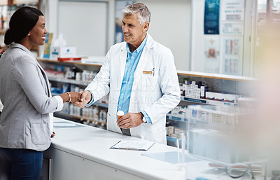 Buy stock photo Shot of a male pharmacist assisting a customer in a chemist