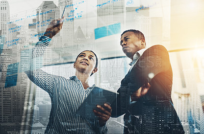 Buy stock photo Shot of two businesspeople brainstorming with notes on a glass wall in an office