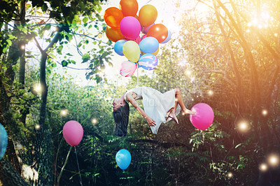 Buy stock photo Shot of a little girl floating in the air with helium balloons around her waist in a forest