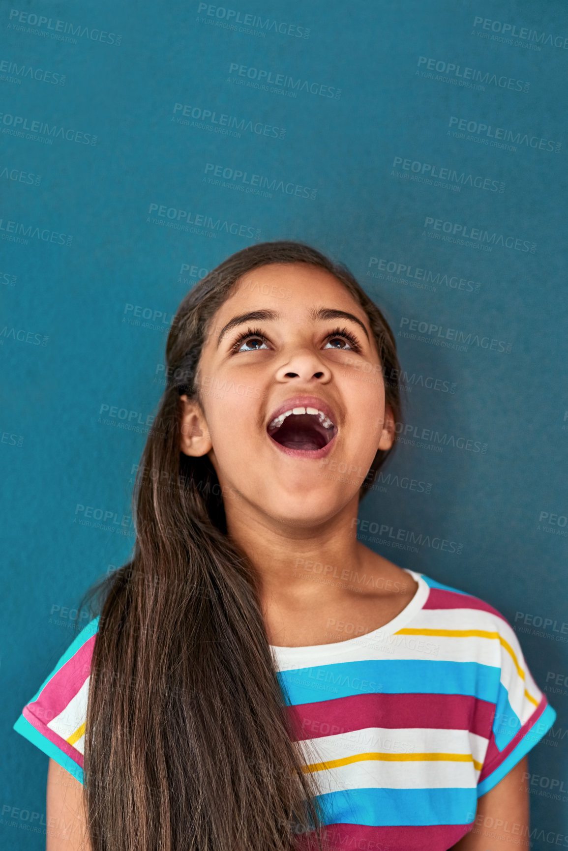 Buy stock photo Wow, happy and child looking up in studio for omg news, opinion and feedback on blue background. Mockup space, surprise and isolated, excited and young girl with announcement, information and deal