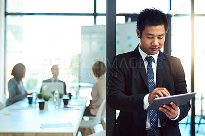 Buy stock photo Cropped shot of a handsome young businessman using a tablet in the workplace