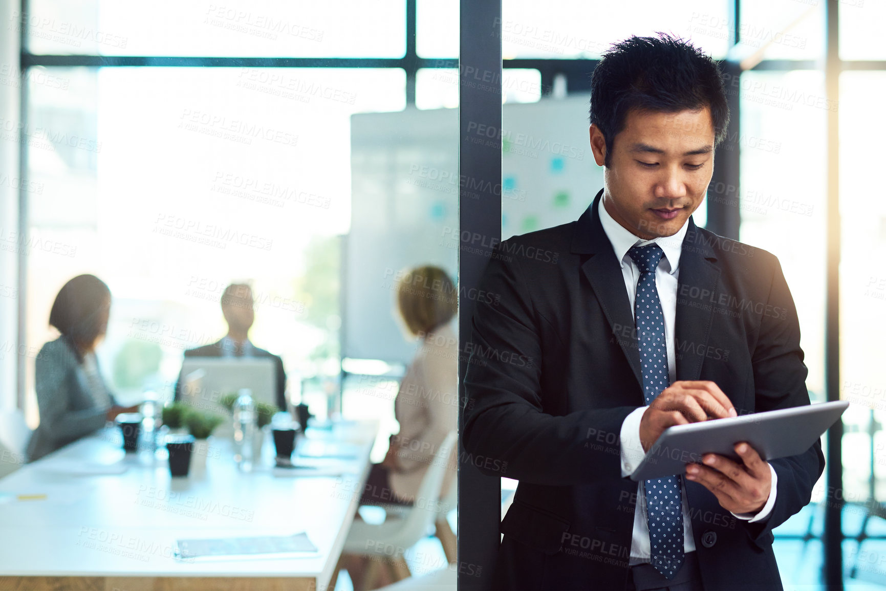 Buy stock photo Cropped shot of a handsome young businessman using a tablet in the workplace