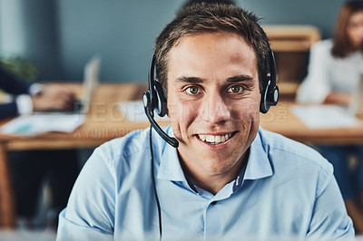 Buy stock photo Portrait of a focussed young man talking to a customer over the phone while using a headset inside the office during the day