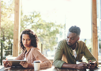 Buy stock photo Shot of two young people using their wireless devices in a coffee shop