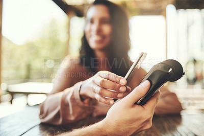 Buy stock photo Cropped shot of a young woman making a wireless payment in a coffee shop