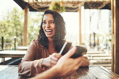Buy stock photo Shot of a female customer making a wireless payment in a coffee shop