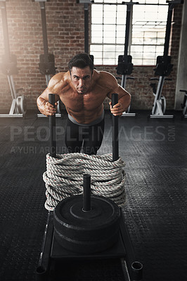 Buy stock photo Shot of a muscular young man pushing a weight sled in a gym