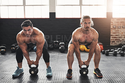 Buy stock photo Shot of two muscular young men lifting weights in a gym
