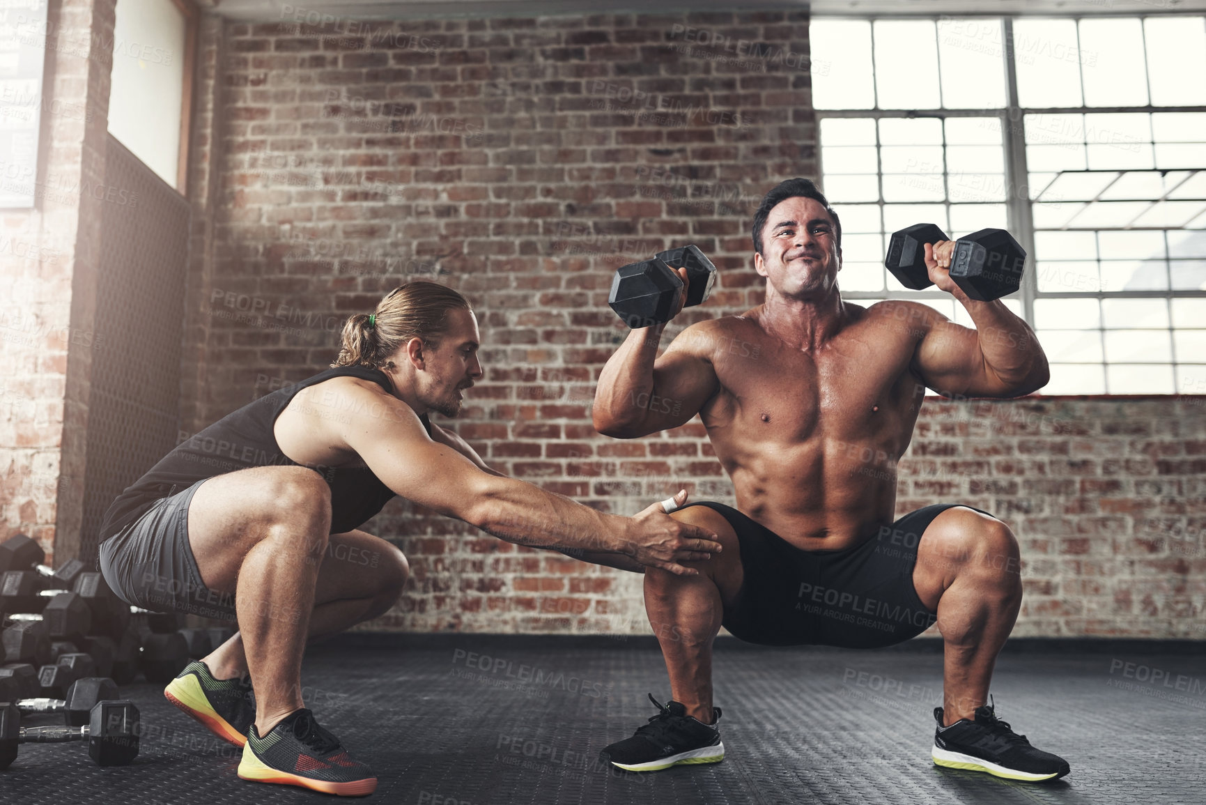 Buy stock photo Shot of a muscular young man working out with his fitness trainer in a gym