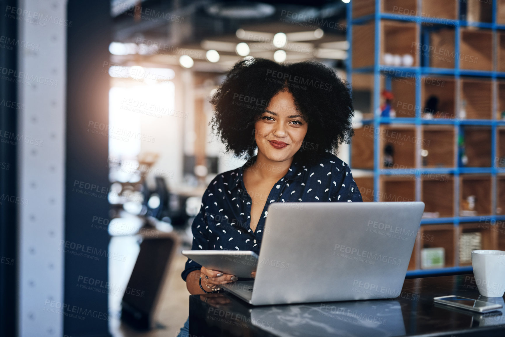 Buy stock photo Portrait of a young focussed female designer working on her laptop and digital tablet at the office during the day