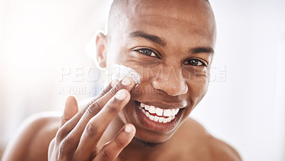 Buy stock photo Portrait of a handsome young man applying moisturizer to his face in the bathroom at home