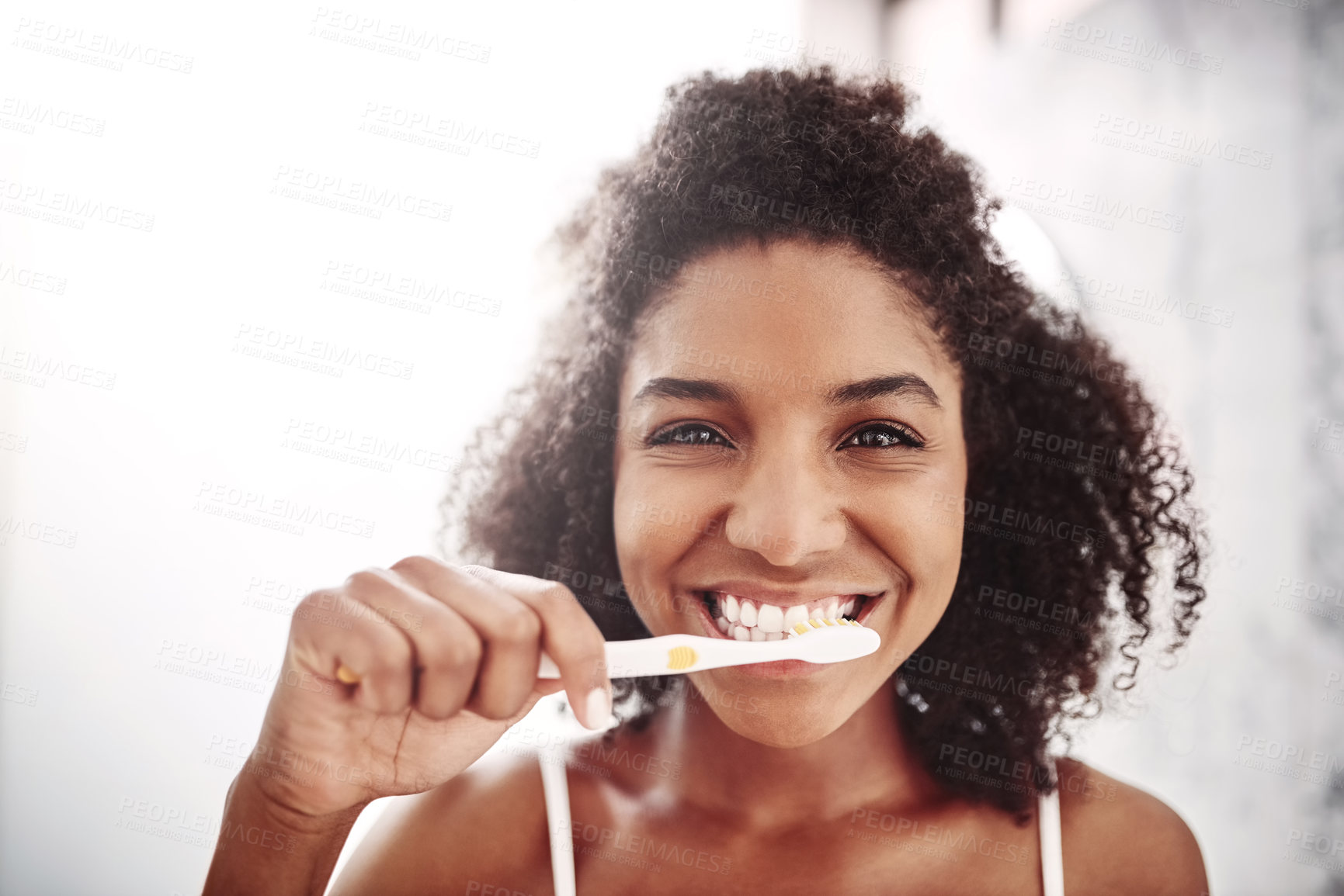 Buy stock photo Portrait of an attractive young woman brushing her teeth in the bathroom at home