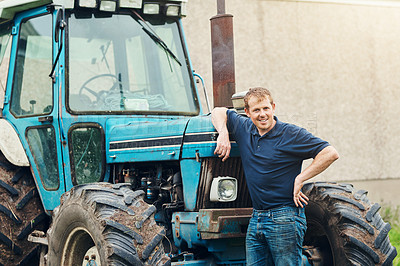 Buy stock photo Portrait of a cheerful young male farmer posing next to his tractor outside on his land