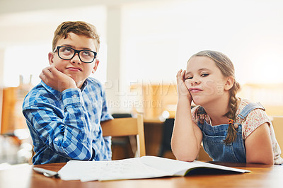 Buy stock photo Shot of two young children working together at school while looking bored inside the classroom