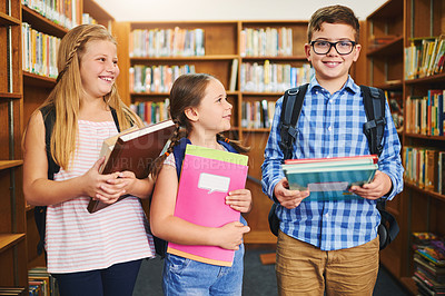 Buy stock photo Shot of a group of young school kids holding books while standing inside of a library together during the day