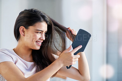Buy stock photo Shot of a beautiful young woman brushing her hair in the bathroom at home