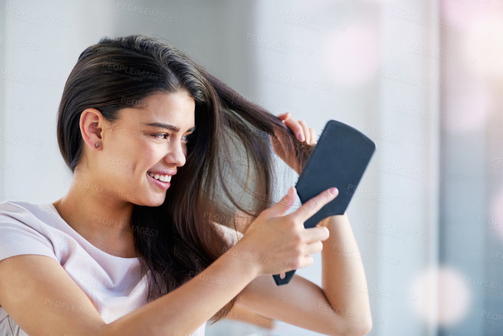 Buy stock photo Shot of a beautiful young woman brushing her hair in the bathroom at home