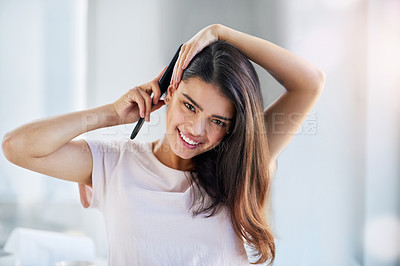 Buy stock photo Portrait of a beautiful young woman brushing her hair in the bathroom at home