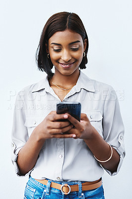 Buy stock photo Studio shot of a young creative businesswoman using her cellphone and posing against a grey background