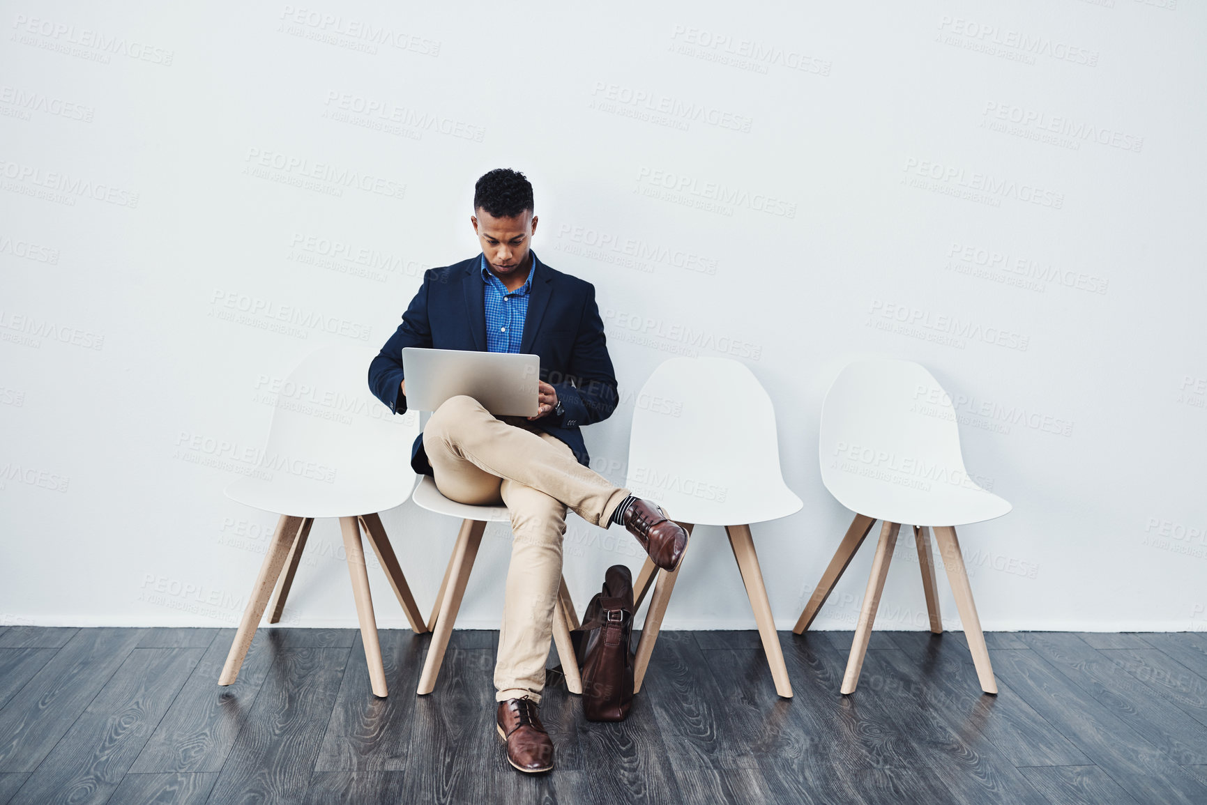 Buy stock photo Full length studio shot of a young businessman sitting down on a chair and using his laptop