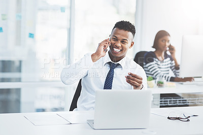 Buy stock photo Shot of two young businesspeople sitting at their office desks making phone calls