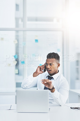 Buy stock photo Shot of a young businessman talking on a cellphone while sitting at his office desk