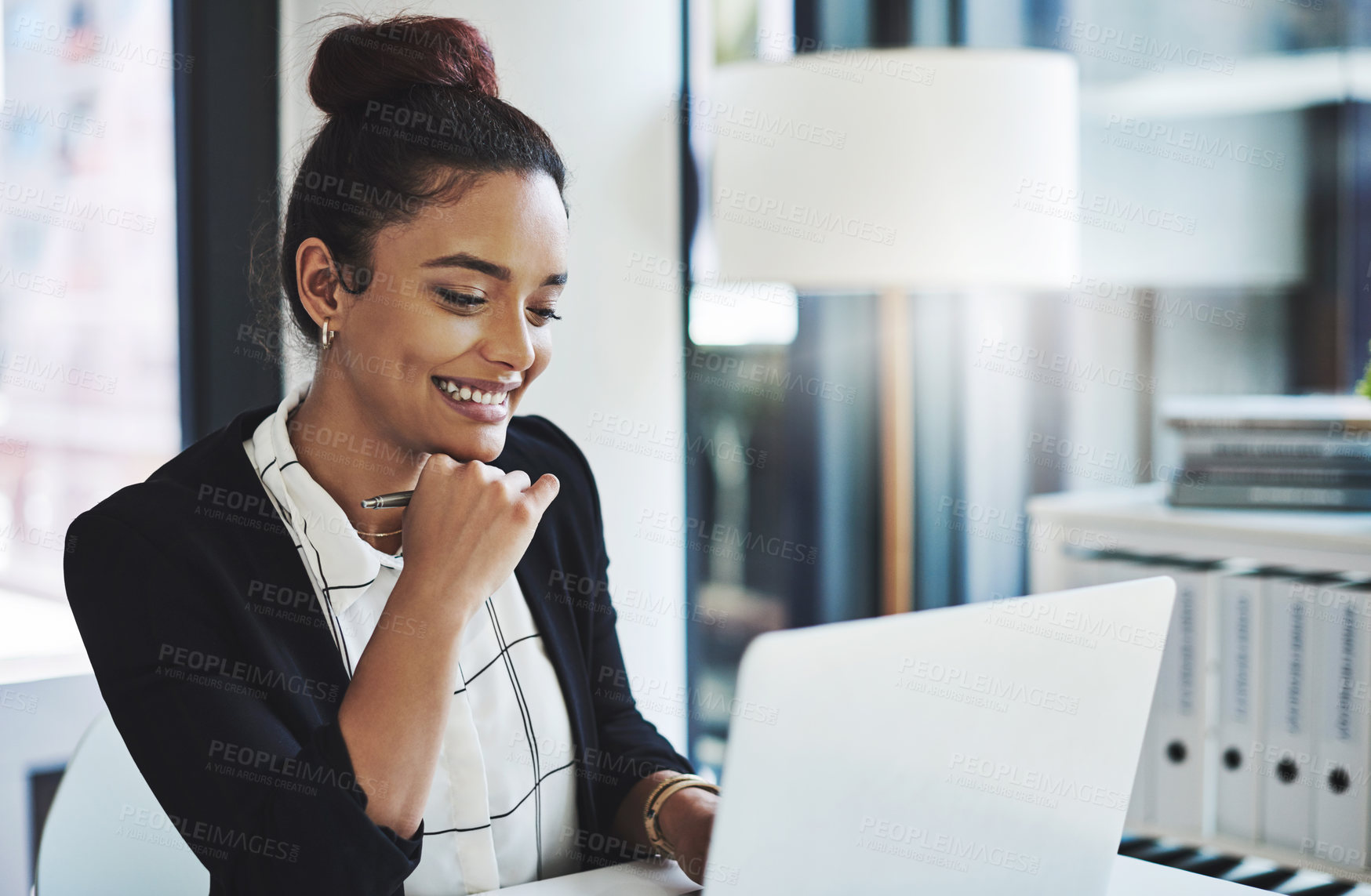 Buy stock photo Shot of a young businesswoman using a laptop in a modern office