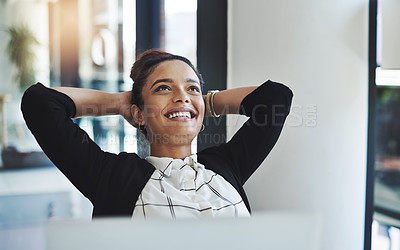 Buy stock photo Shot of a young businesswoman relaxing at her desk in a modern office