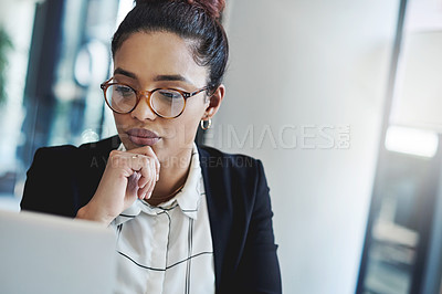 Buy stock photo Shot of a young businesswoman using a laptop in a modern office