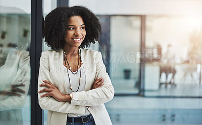 Buy stock photo Shot of a young businesswoman looking out of a window and posing with her arms folded in her office