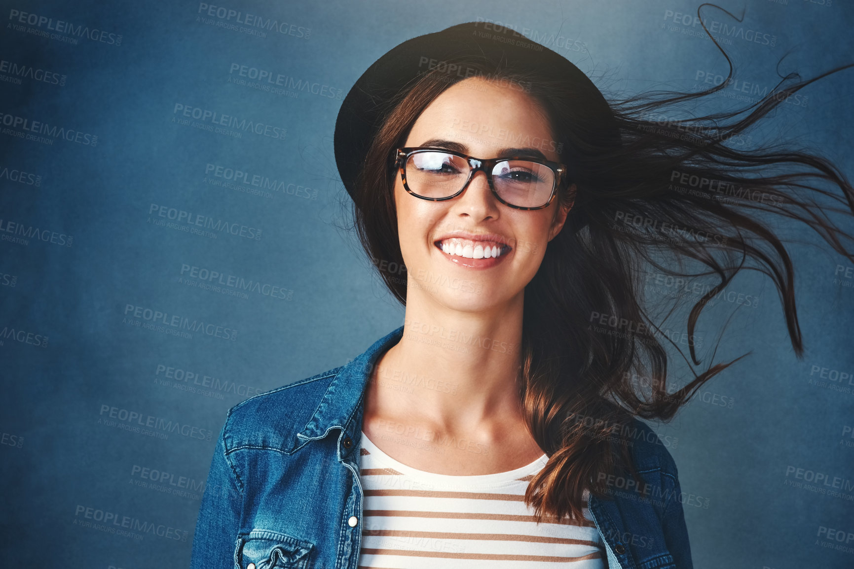 Buy stock photo Studio portrait of an attractive young woman smiling against a blue background
