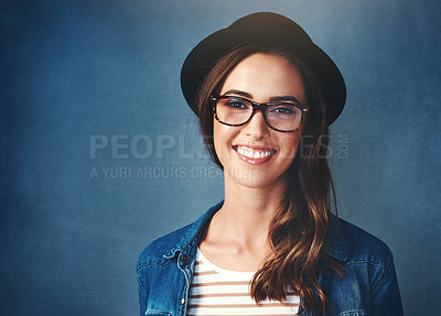 Buy stock photo Studio portrait of an attractive young woman smiling against a blue background