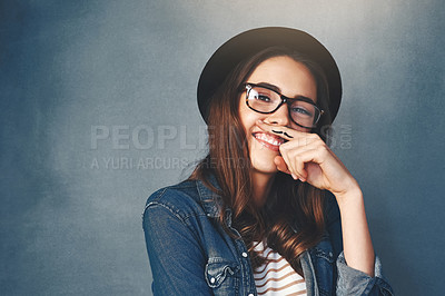 Buy stock photo Studio shot of an attractive young woman making a finger moustache against a blue background