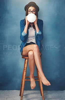 Buy stock photo Studio shot of an attractive young woman blowing up a balloon against a blue background