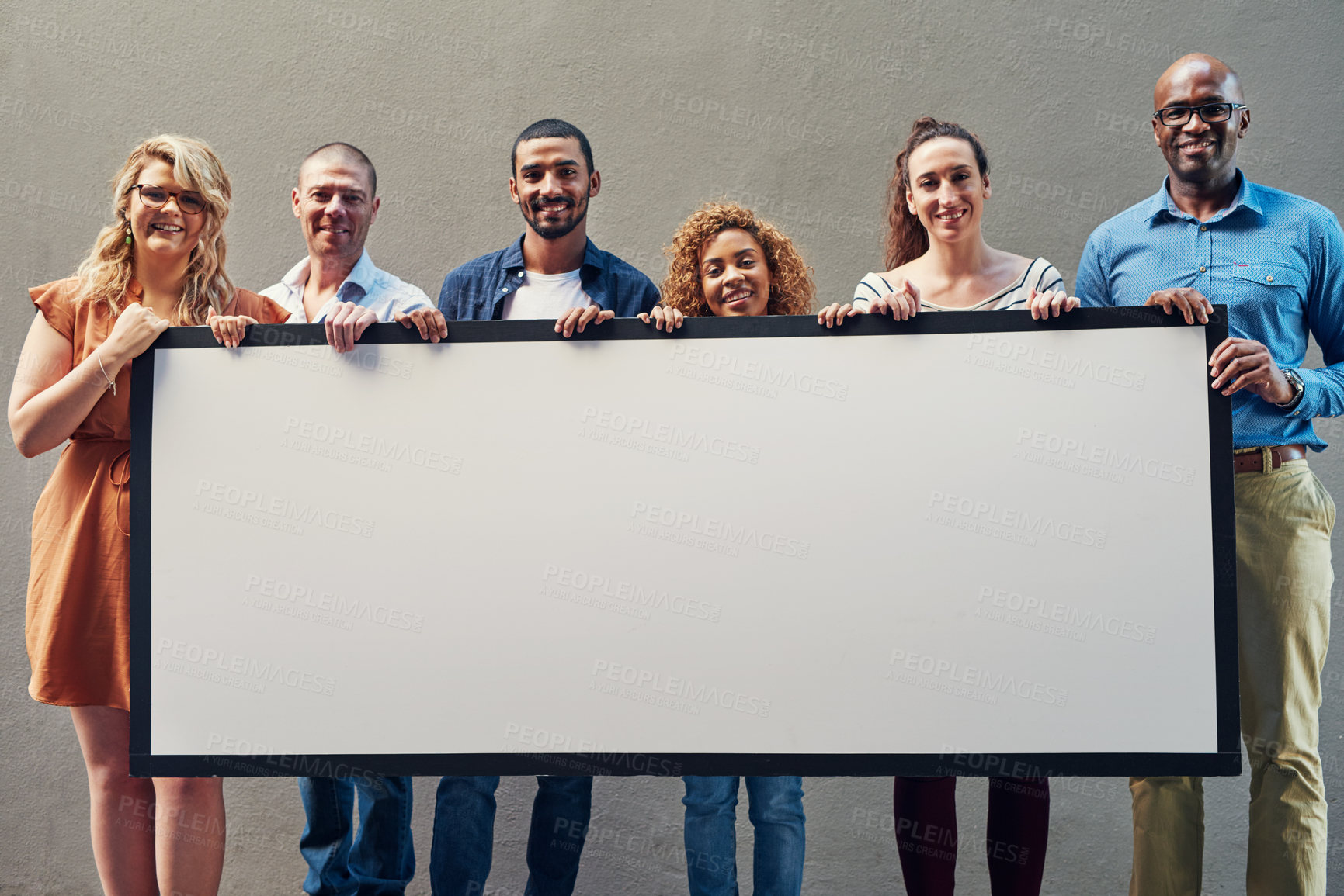 Buy stock photo Portrait of a group of people holding a blank sign against a wall outside