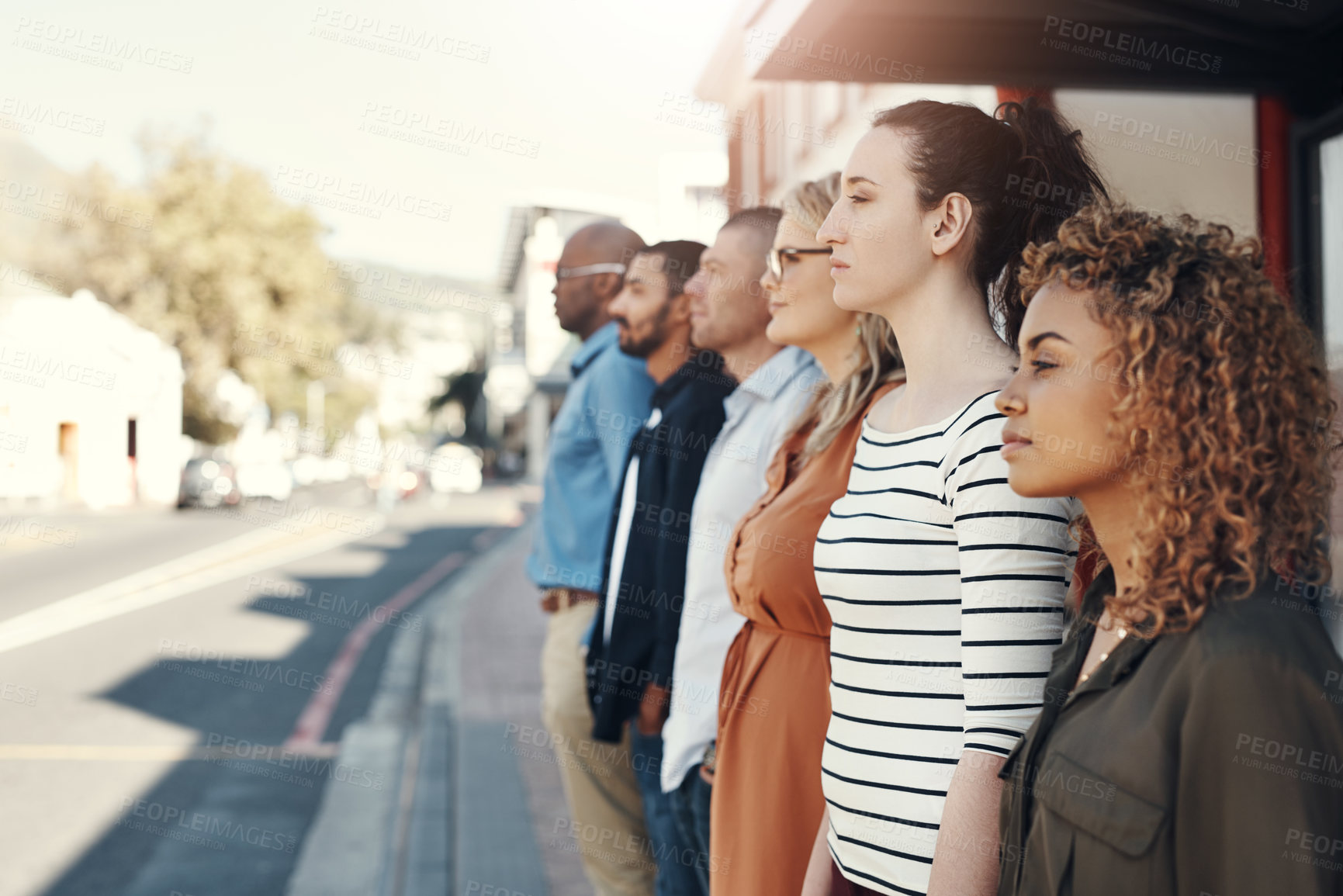 Buy stock photo Shot of a group of people standing in a line in the city
