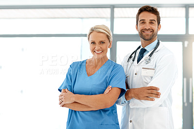 Buy stock photo Cropped portrait of two happy healthcare practitioners standing with their arms folded in the hospital