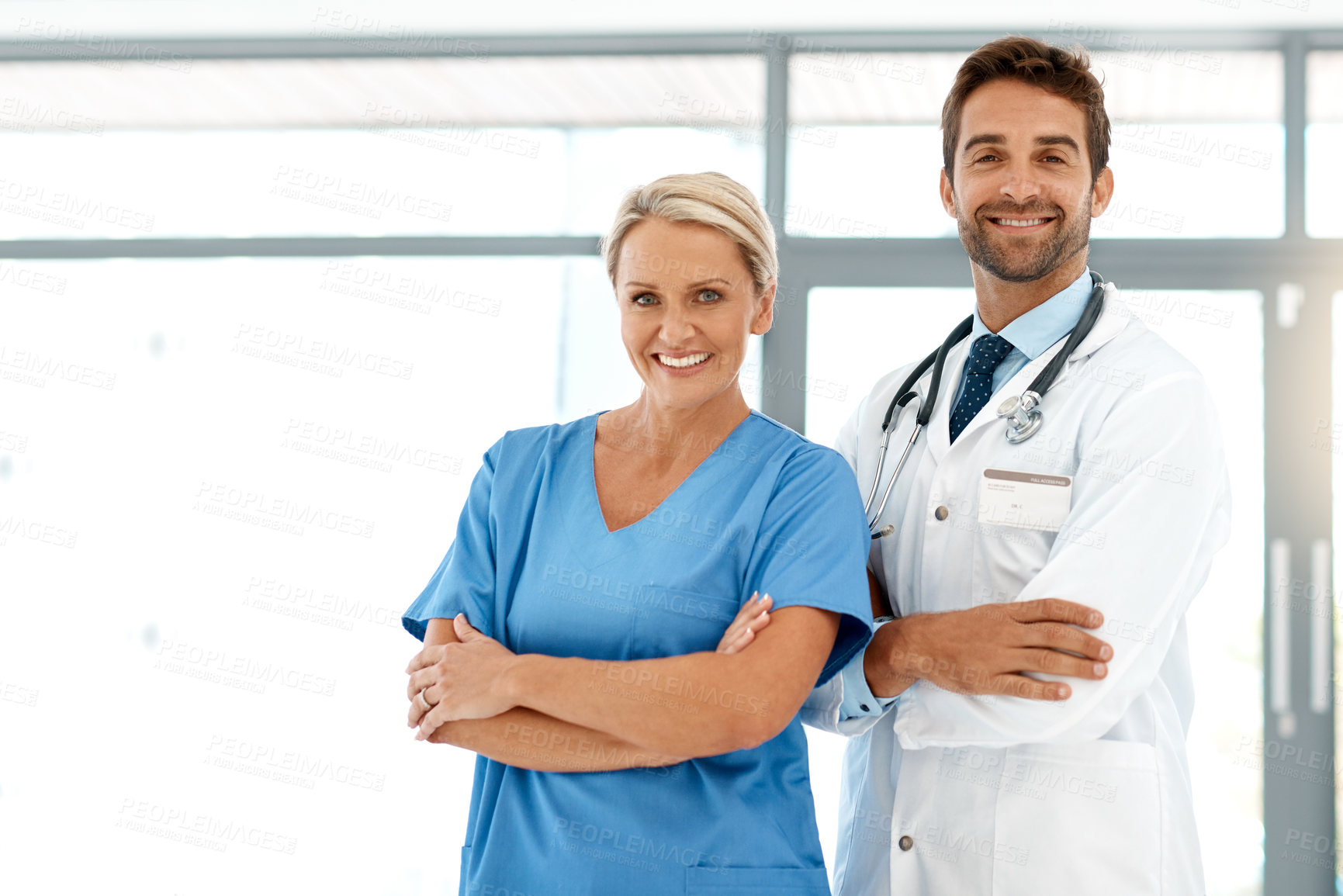 Buy stock photo Cropped portrait of two happy healthcare practitioners standing with their arms folded in the hospital