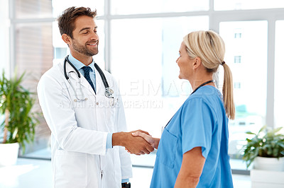 Buy stock photo Cropped shot of two healthcare practitioners shaking hands in the hospital foyer