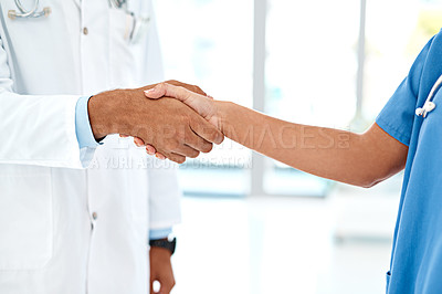 Buy stock photo Cropped shot of two unidentifiable healthcare practitioners shaking hands in the hospital foyer