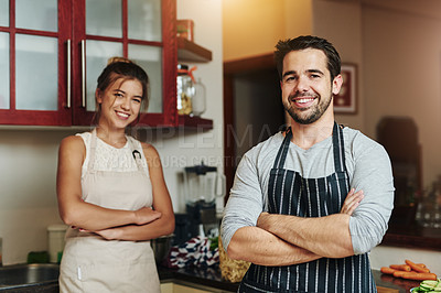 Buy stock photo Cropped portrait of a young couple standing with their arms folded and smiling in the kitchen