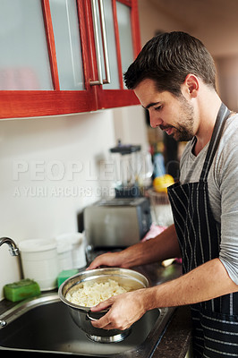 Buy stock photo Cropped shot of a handsome young man draining pasta at home