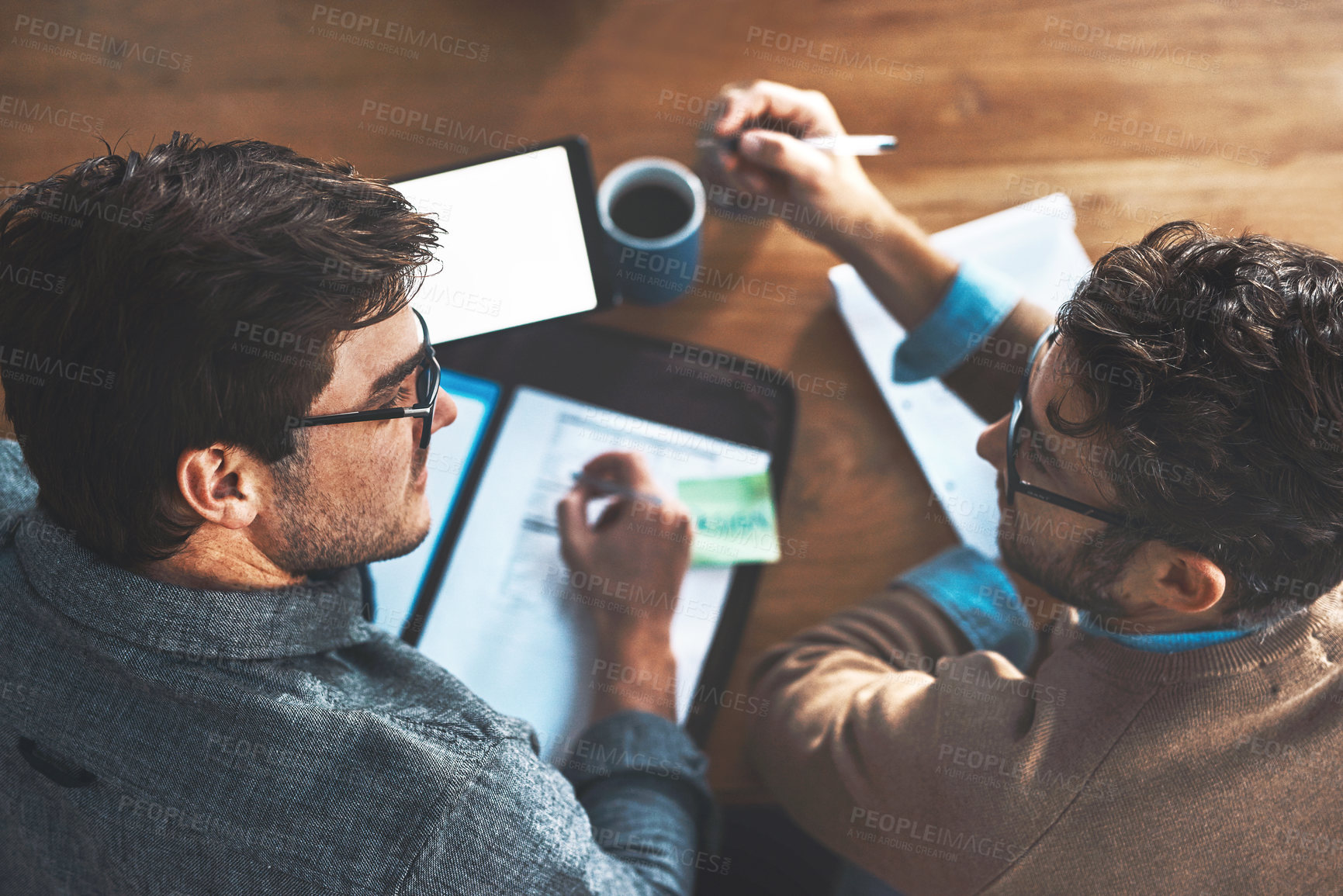 Buy stock photo High angle shot of two businessmen going over paperwork together at work