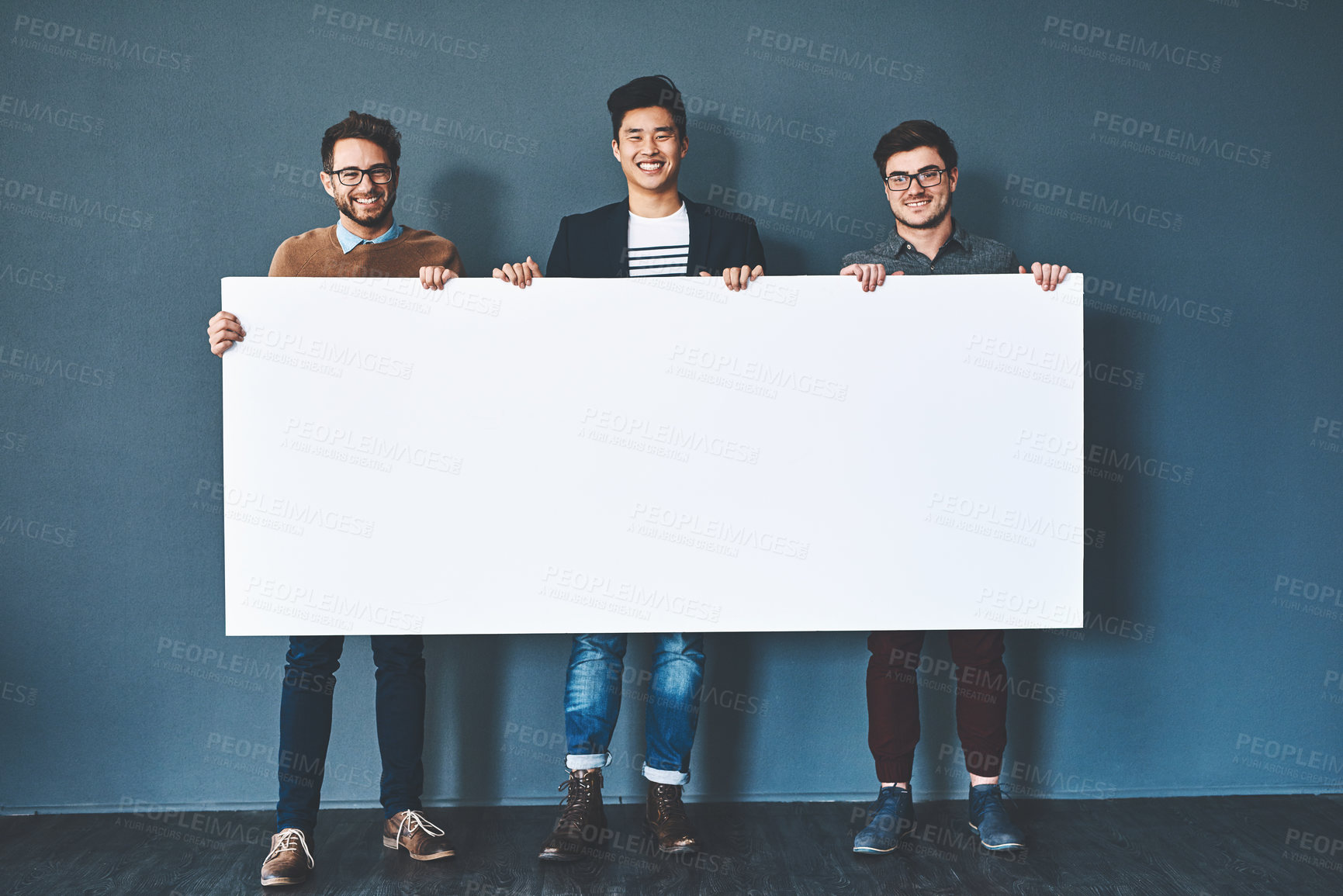 Buy stock photo Studio shot of businesspeople holding up a blank sign against a grey background