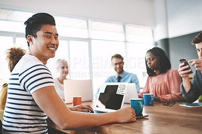 Buy stock photo Shot of a young businessman using a laptop during a meeting in a modern office