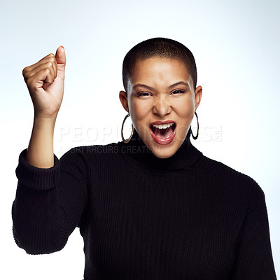 Buy stock photo Studio shot of an attractive young woman posing with her arm raised and fist clinched against a grey background