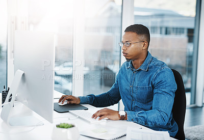 Buy stock photo Shot of a young businessman working at his desk in a modern office