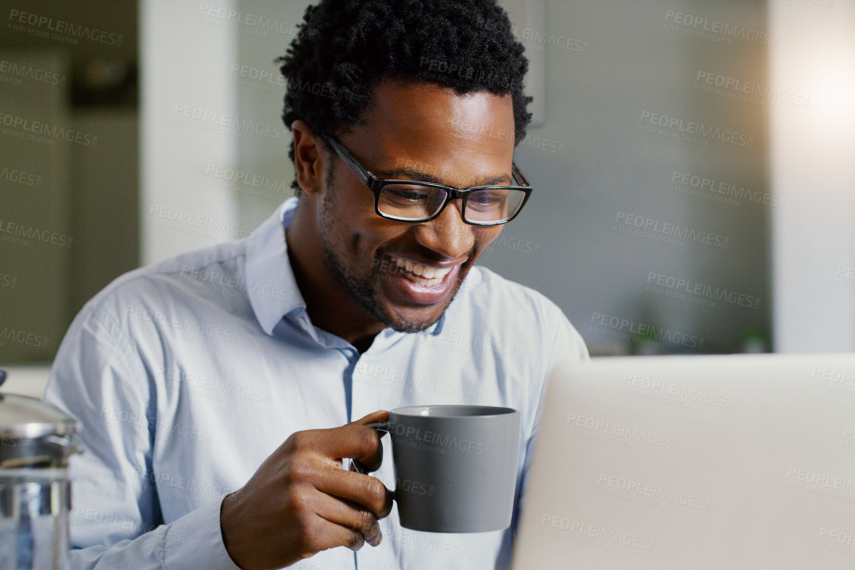 Buy stock photo Shot of a handsome young businessman working on his laptop at home