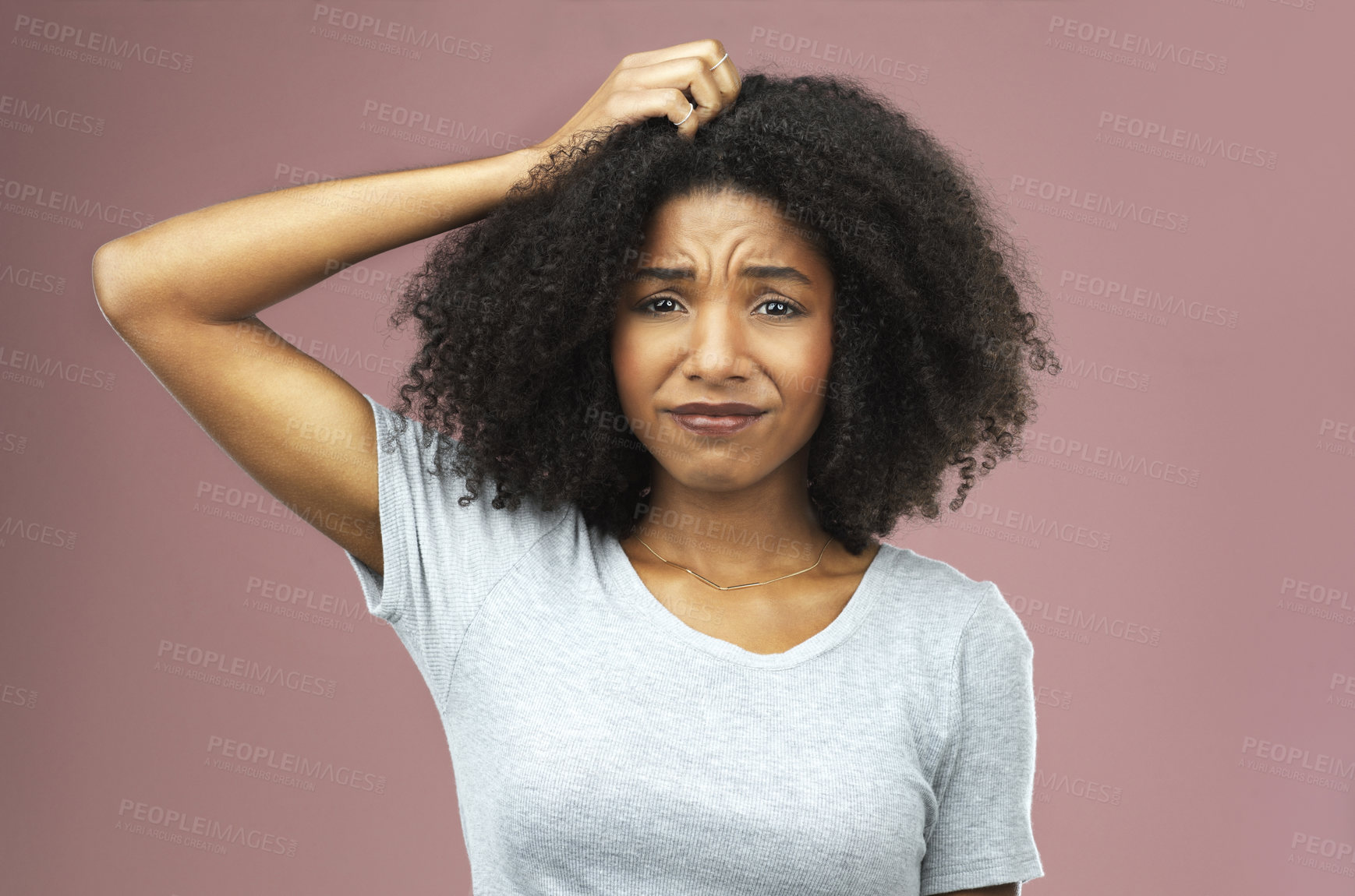 Buy stock photo Studio shot of an attractive young woman looking unsure against a pink background